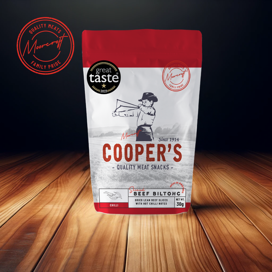 A striking image of Cooper's Beef Biltong package on a wooden surface, highlighting the brand's commitment to quality with the 'Great Taste 2023' award emblem and 'Family Pride' seal.