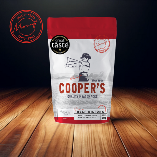 A striking image of Cooper's Beef Biltong package on a wooden surface, highlighting the brand's commitment to quality with the 'Great Taste 2023' award emblem and 'Family Pride' seal. 